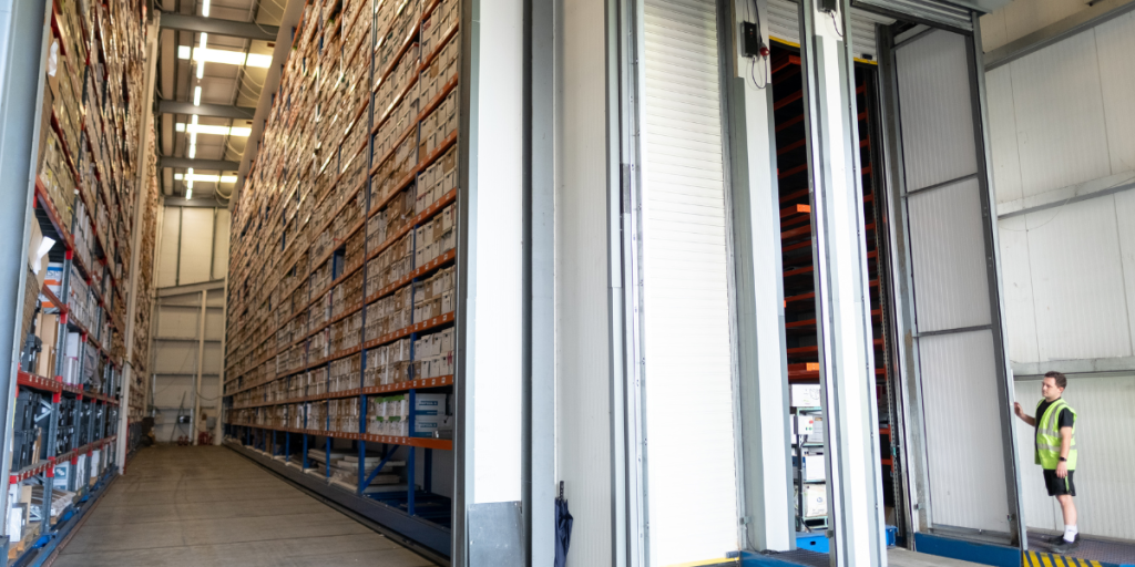Picture of a document storage warehouse, with lots of stacked document boxes and a temperature controlled vault on the right side.
